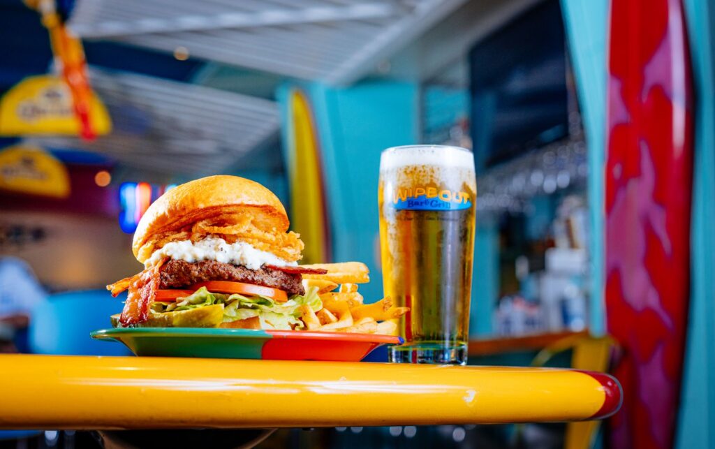 A burger next to a cold beer in a glass
